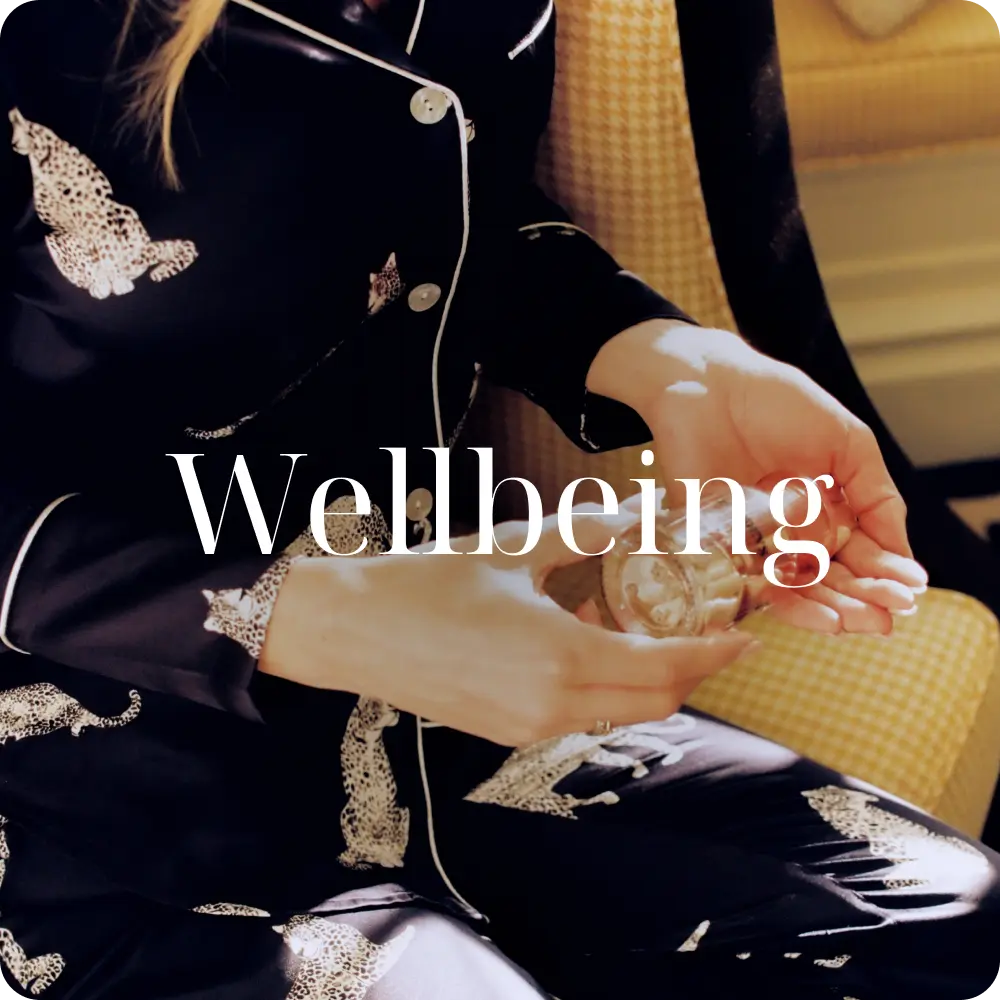 Image of woman in blue pyjamas pouring Wake-Up Call into hands with the text 'wellbeing' over the top