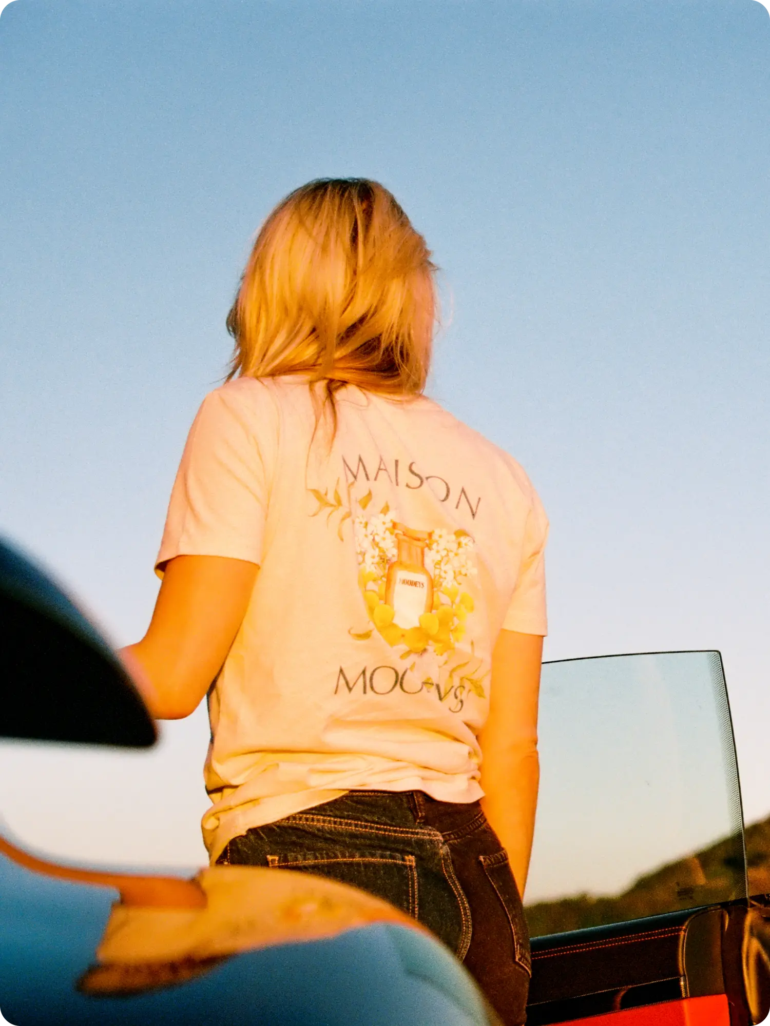 Blonde woman in the sunset with a Maison Moodeys beige flower tee