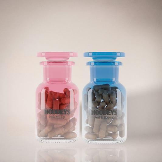 Two glass jars, one pink and one blue, filled with rest and repeat and pick me up on a light background.